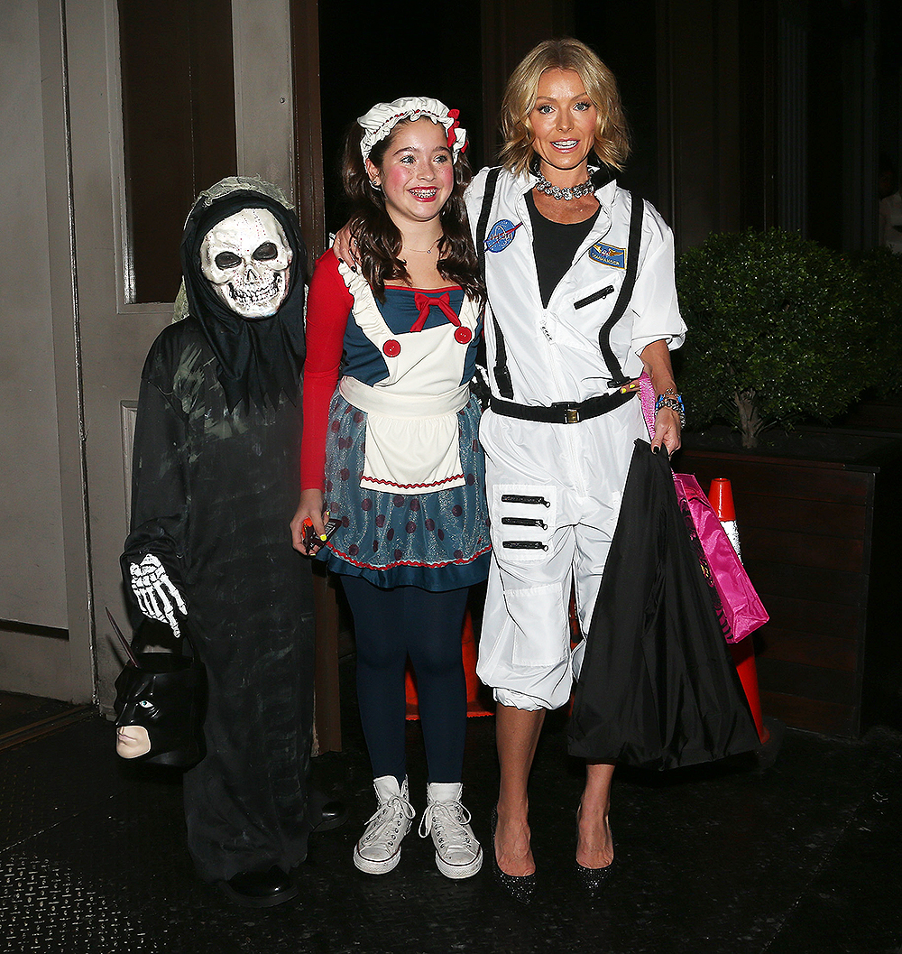 Kelly Ripa, dressed up as an astronaut, poses with her kids Joaquin and Lola outside her apartment on Halloween