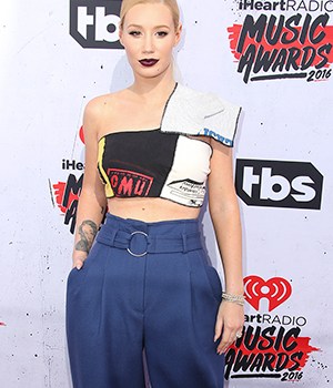 Iggy Azalea wearing a crop top and blue pants