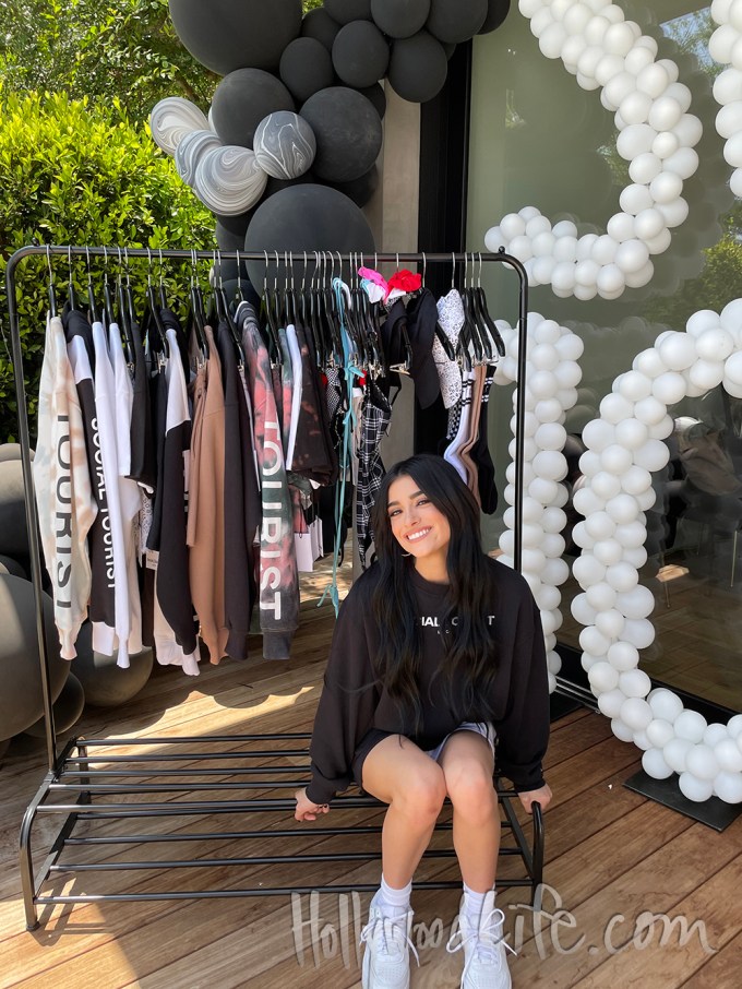 Dixie Smiles In Front Of A Rack Of Social Tourist Merch