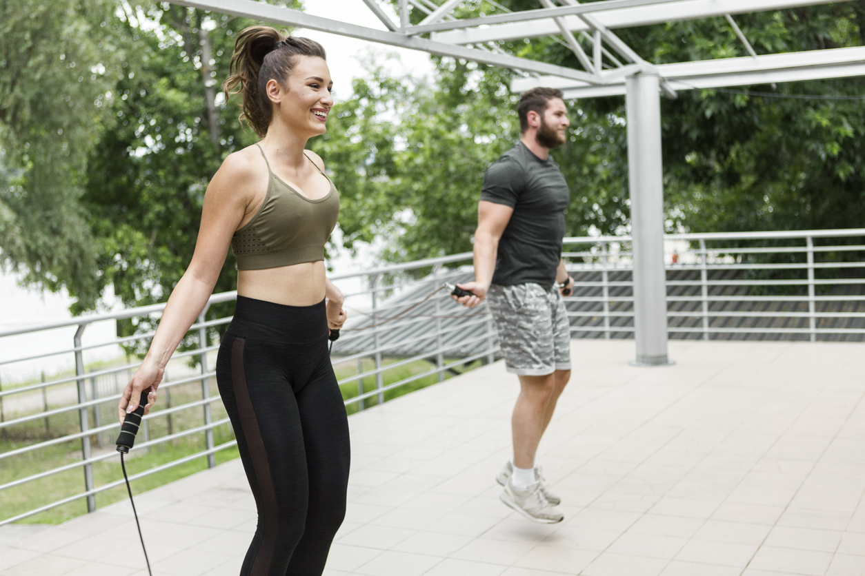 A man and woman workout outside with a pair of jump ropes.