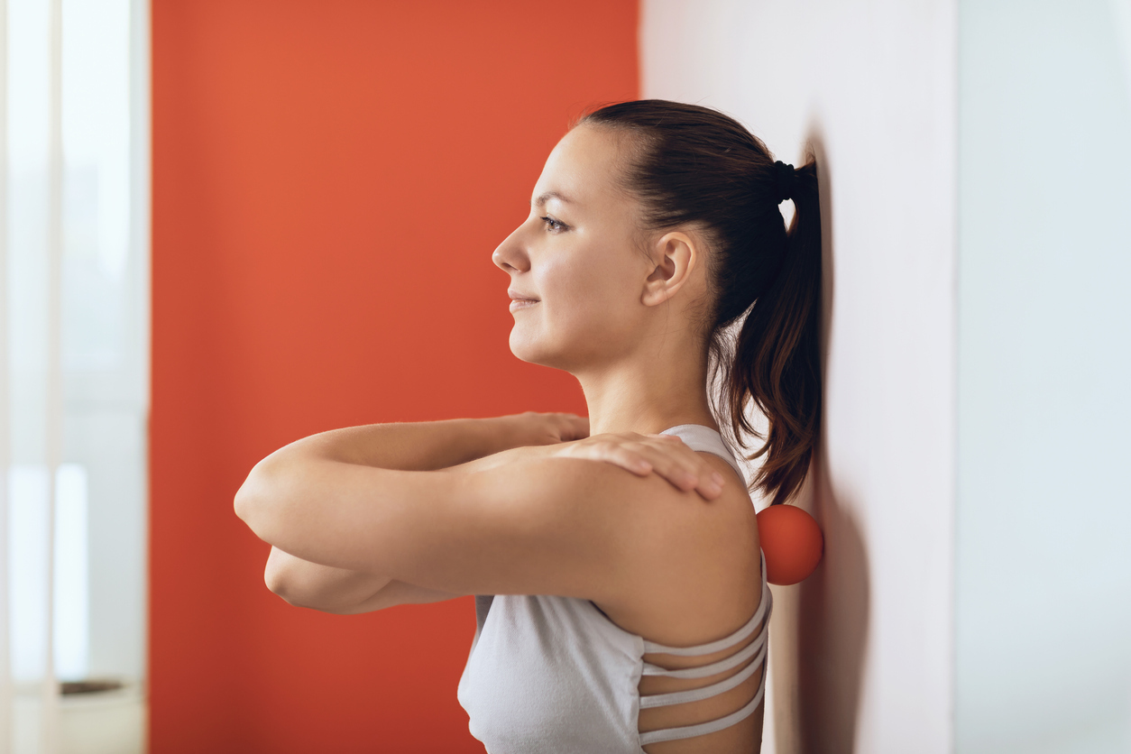 A woman massages her back with massage balls