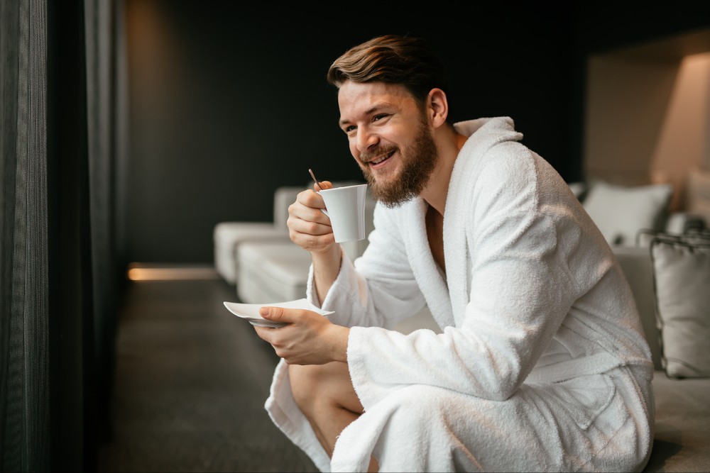 Handsome man drinking tea and relaxing in bathrobe