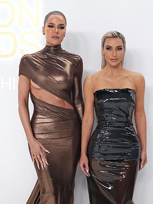 Khloe Kardashian and Kim Kardashian posting at event.
