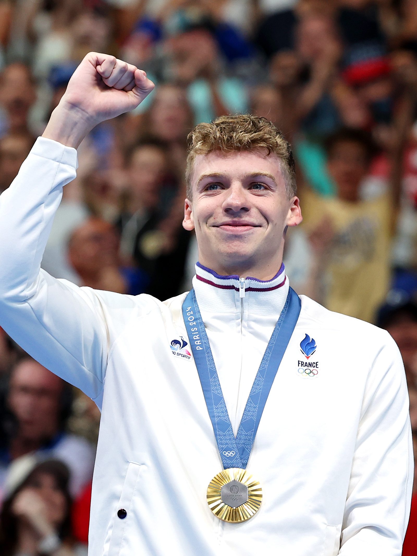 NANTERRE, FRANCE - JULY 28: Gold Medalist Leon Marchand of Team France celebrates on the podium during the Swimming medal ceremony after the Men’s 400m Individual Medley Final on day two of the Olympic Games Paris 2024 at Paris La Defense Arena on July 28, 2024 in Nanterre, France. (Photo by Quinn Rooney/Getty Images)