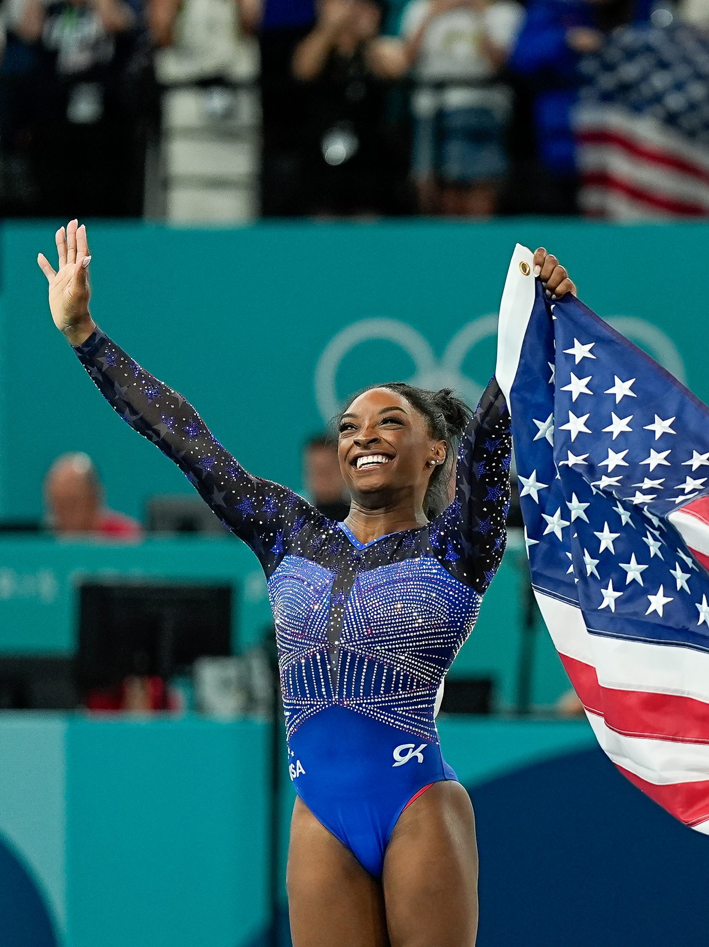 PARIS, FRANCE - AUGUST 1: Simone Biles of United States (L) and Sunisa Lee of United States (R) celebrate their victory and third place holding the USA flag during the Women's All-Around Final on day six of the Olympic Games Paris 2024 at Bercy Arena on August 1, 2024 in Paris, France. (Photo by Daniela Porcelli/Eurasia Sport Images/Getty Images)