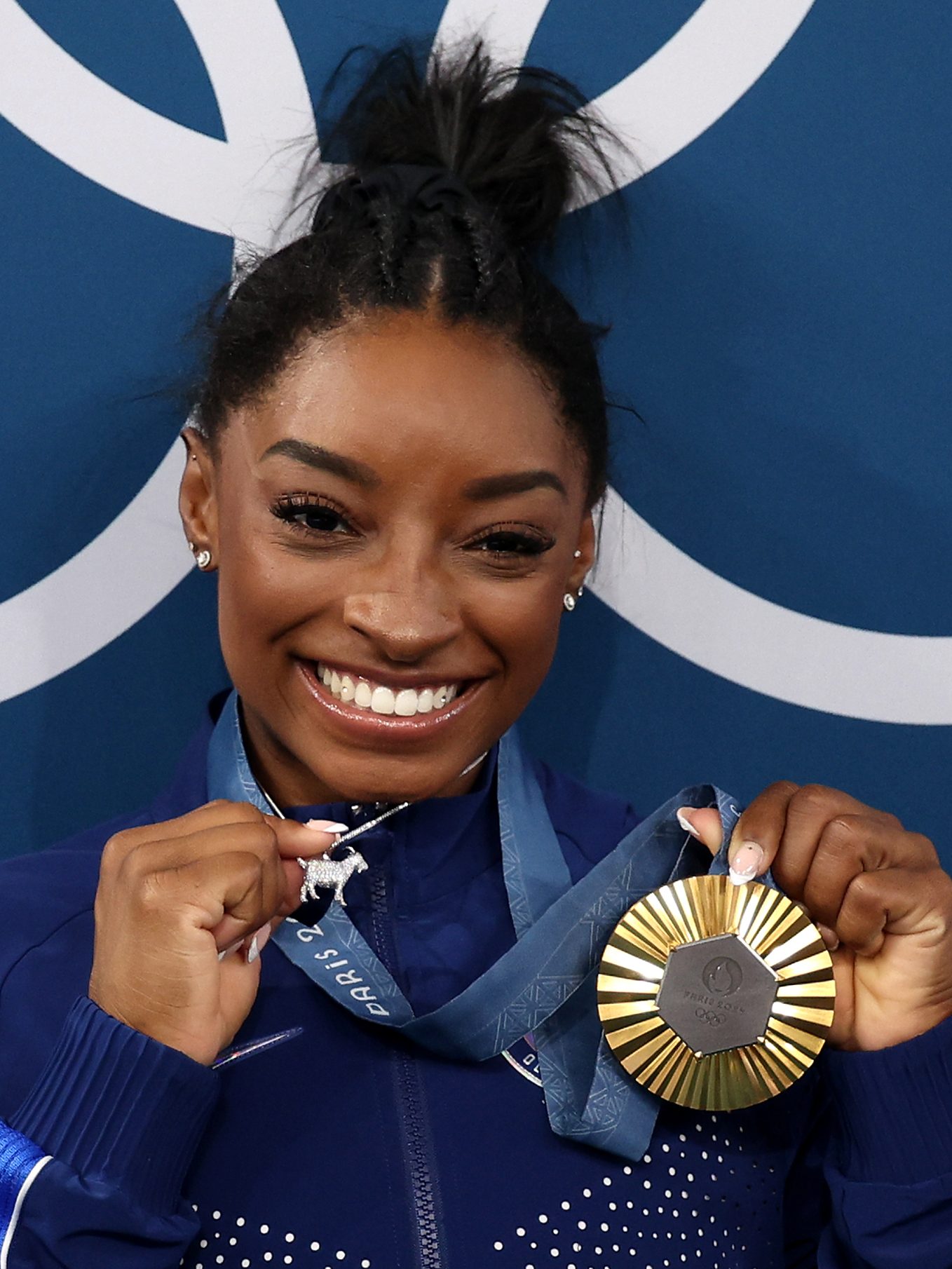 PARIS, FRANCE - AUGUST 01: (EDITOR'S NOTE: Alternate crop) Gold medalist Simone Biles of Team United States poses with the Olympic Rings and a goat charm on her necklace during the Artistic Gymnastics Women's All-Around Final medal ceremony on day six of the Olympic Games Paris 2024 at Bercy Arena on August 01, 2024 in Paris, France. (Photo by Jamie Squire/Getty Images)