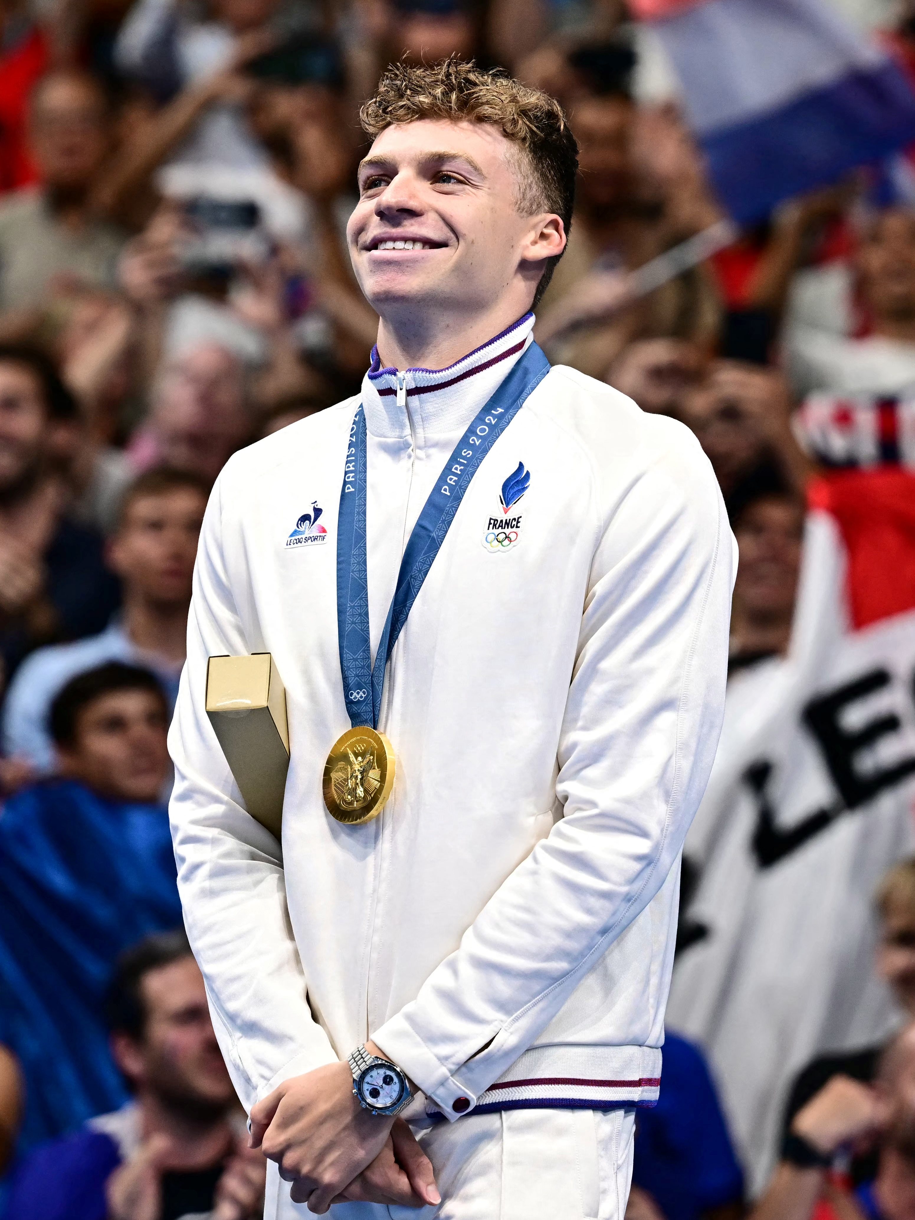 Leon Marchand poses with his medal on the podium of the men's 200m individual medley