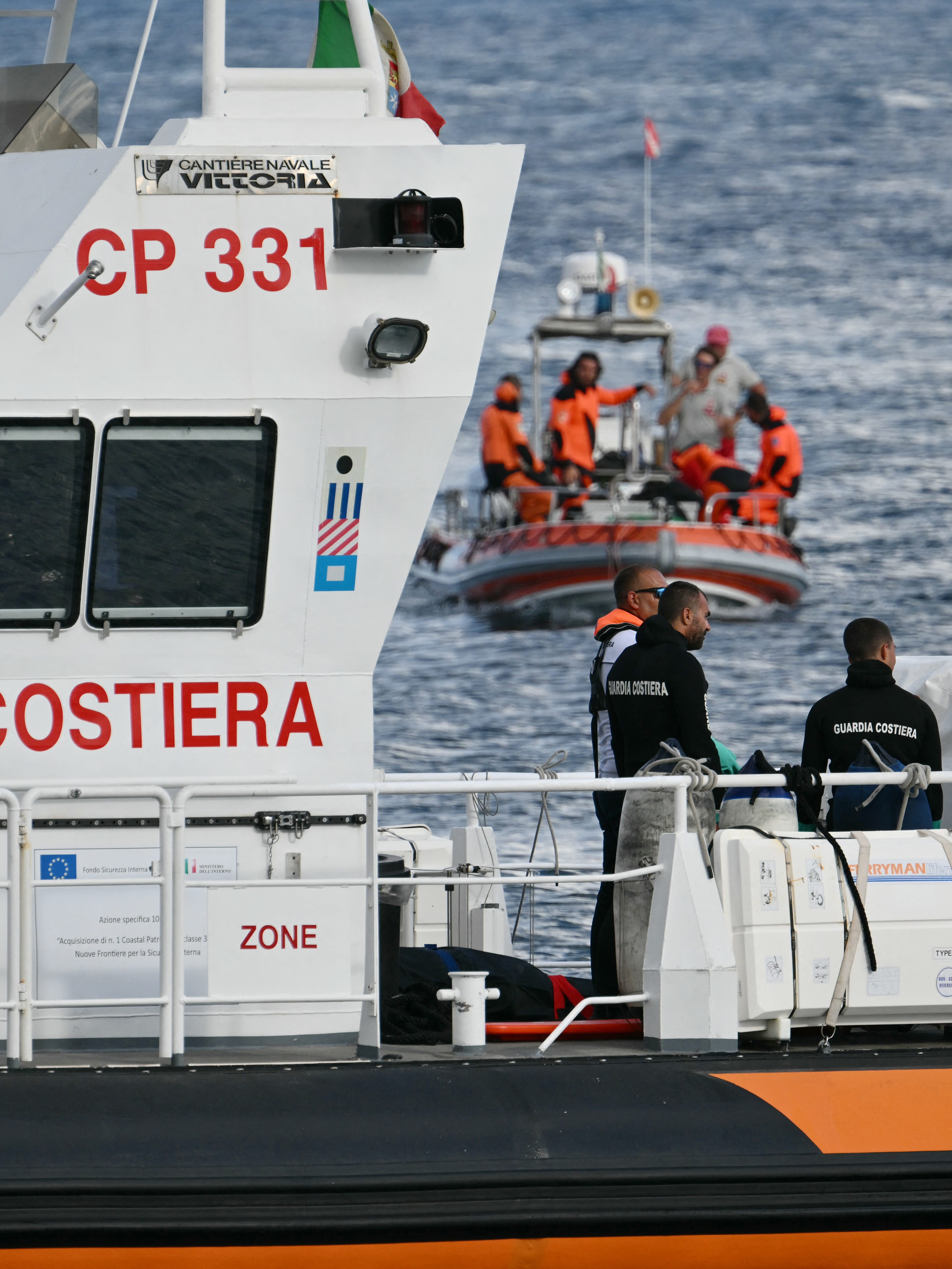 Italian Coast Guards carry a body on a rescue boat in Porticello harbor near Palermo, with a third body at the back of the boat on August 21, 2024, two days after the British-flagged luxury yacht Bayesian sank. Divers searching for six missing people following the sinking of a superyacht off Sicily in a storm have found four bodies, a source close to the search told AFP. The Bayesian, which had 22 people aboard including 10 crew, was anchored some 700 metres from port before dawn when it was struck by a waterspout. Among the six missing were UK tech entrepreneur Mike Lynch and his 18-year-old daughter Hannah, and Jonathan Bloomer, the chair of Morgan Stanley International, and his wife Judy. (Photo by Alberto PIZZOLI / AFP) (Photo by ALBERTO PIZZOLI/AFP via Getty Images)