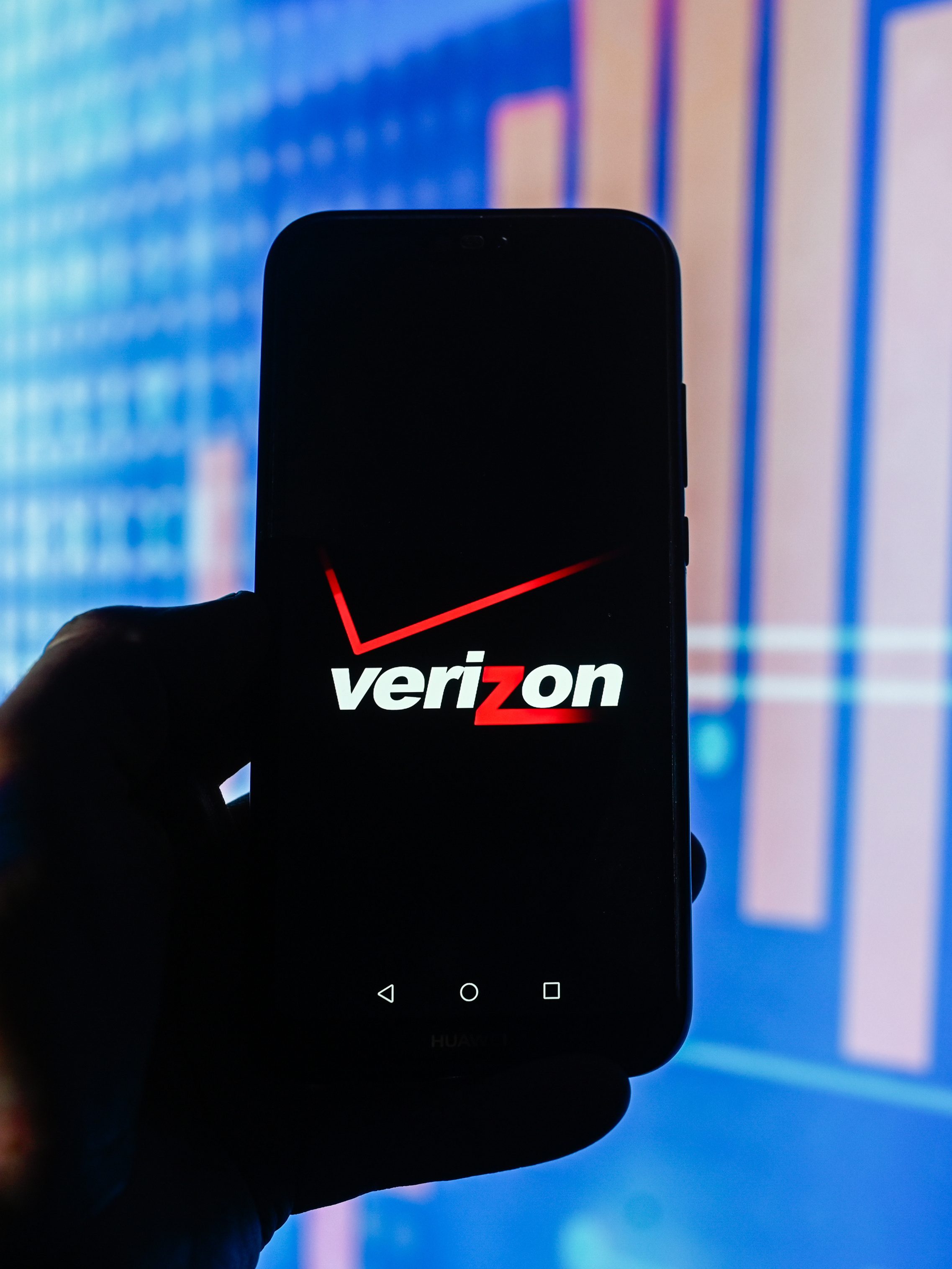 A Verizon logo is displayed on a smartphone with stock market percentages in the background. (Photo Illustration by Omar Marques/SOPA Images/LightRocket via Getty Images)