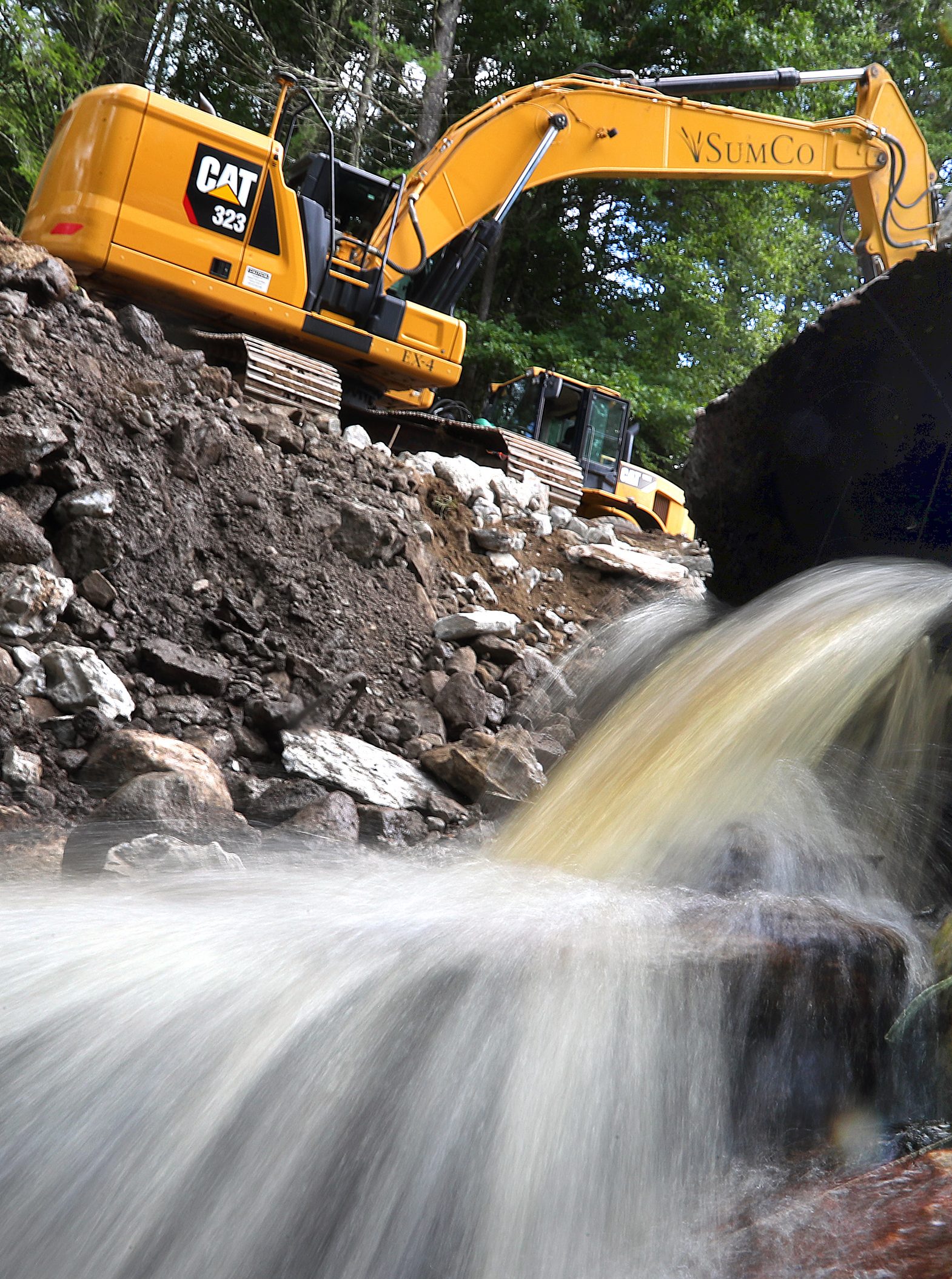 The Dudleyville Pond Dam was taken down by heavy construction equipment after an emergency order because of a high risk of failure. Water poured from a culvert in the dam as it was being removed. (Photo by John Tlumacki/The Boston Globe via Getty Images)