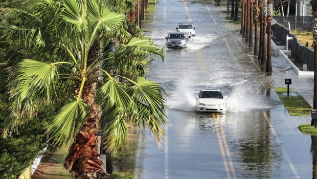 ST. PETE BEACH, FLORIDA - SEPTEMBER 26: In this aerial view, vehicles drive through a flooded street as Hurricane Helene churns offshore on September 26, 2024 in St. Pete Beach, Florida. Later today, Helene is forecast to become a major hurricane, bringing the potential for deadly storm surges, flooding rain, and destructive hurricane-force winds along parts of the Florida West Coast. (Photo by Joe Raedle/Getty Images)