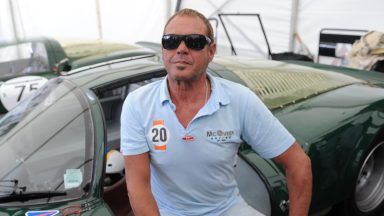 Chad McQueen poses while sitting on a 1966 Porsche 906 i