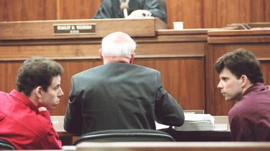 LOS ANGELES, UNITED STATES:  Erik (L) and Lyle (R) Menendez converse in the courtroom during a hearing in Los Angeles, in this 02 February 1995 file picture. They are accused of murdering their parents in 1989. (Photo credit should read KIM KULISH/AFP via Getty Images)