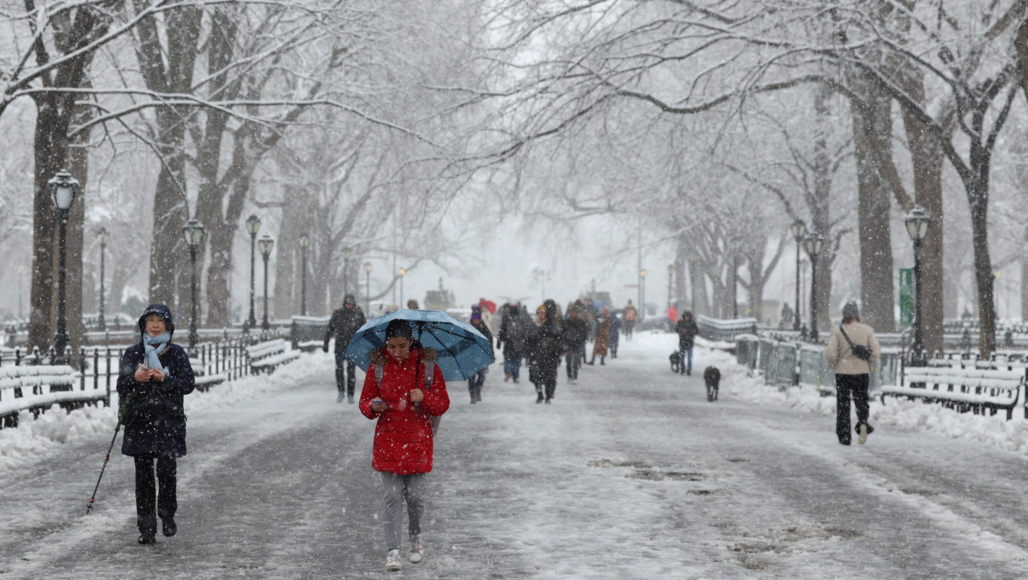 People walk through the falling snow in Central Park on February 13, 2024 in New York City. Heavy snowfall is expected over parts of the Northeast US starting late February 12, with some areas getting up to two inches (5cms) of snow an hour, the National Weather Service forecasters said. (Photo by Yuki IWAMURA / AFP) (Photo by YUKI IWAMURA/AFP via Getty Images)