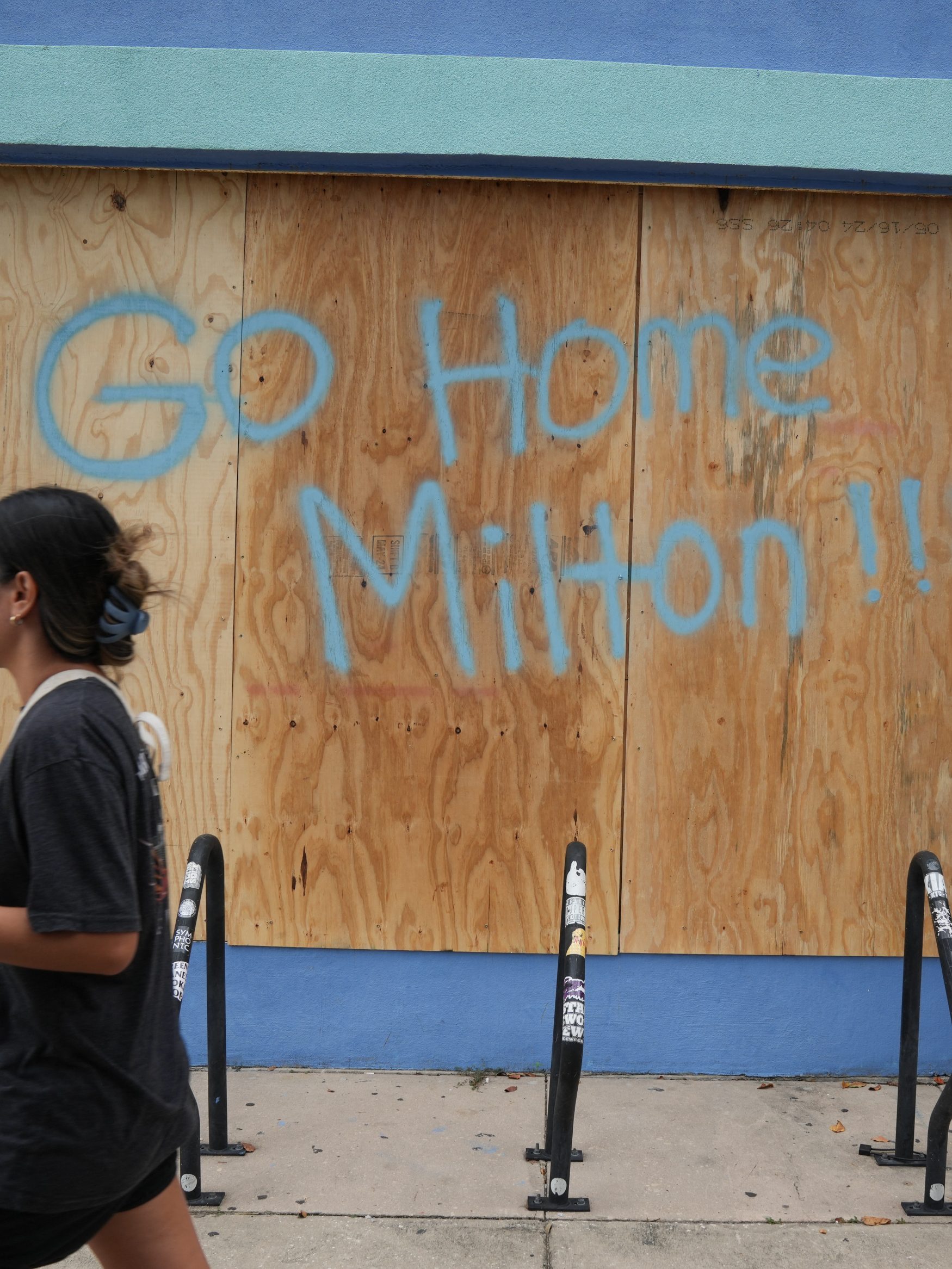 People walk past boarded up storefronts in Tampa ahead of Hurricane Milton's expected landfall in the middle of this week on October 8, 2024 in Florida. Hurricane Milton exploded in strength October 7 to become a potentially catastrophic Category 5 storm bound for Florida, threatening the US state with a second ferocious hurricane in as many weeks. (Photo by Bryan R. SMITH / AFP) (Photo by BRYAN R. SMITH/AFP via Getty Images)