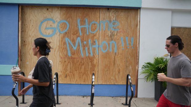 People walk past boarded up storefronts in Tampa ahead of Hurricane Milton's expected landfall in the middle of this week on October 8, 2024 in Florida. Hurricane Milton exploded in strength October 7 to become a potentially catastrophic Category 5 storm bound for Florida, threatening the US state with a second ferocious hurricane in as many weeks. (Photo by Bryan R. SMITH / AFP) (Photo by BRYAN R. SMITH/AFP via Getty Images)