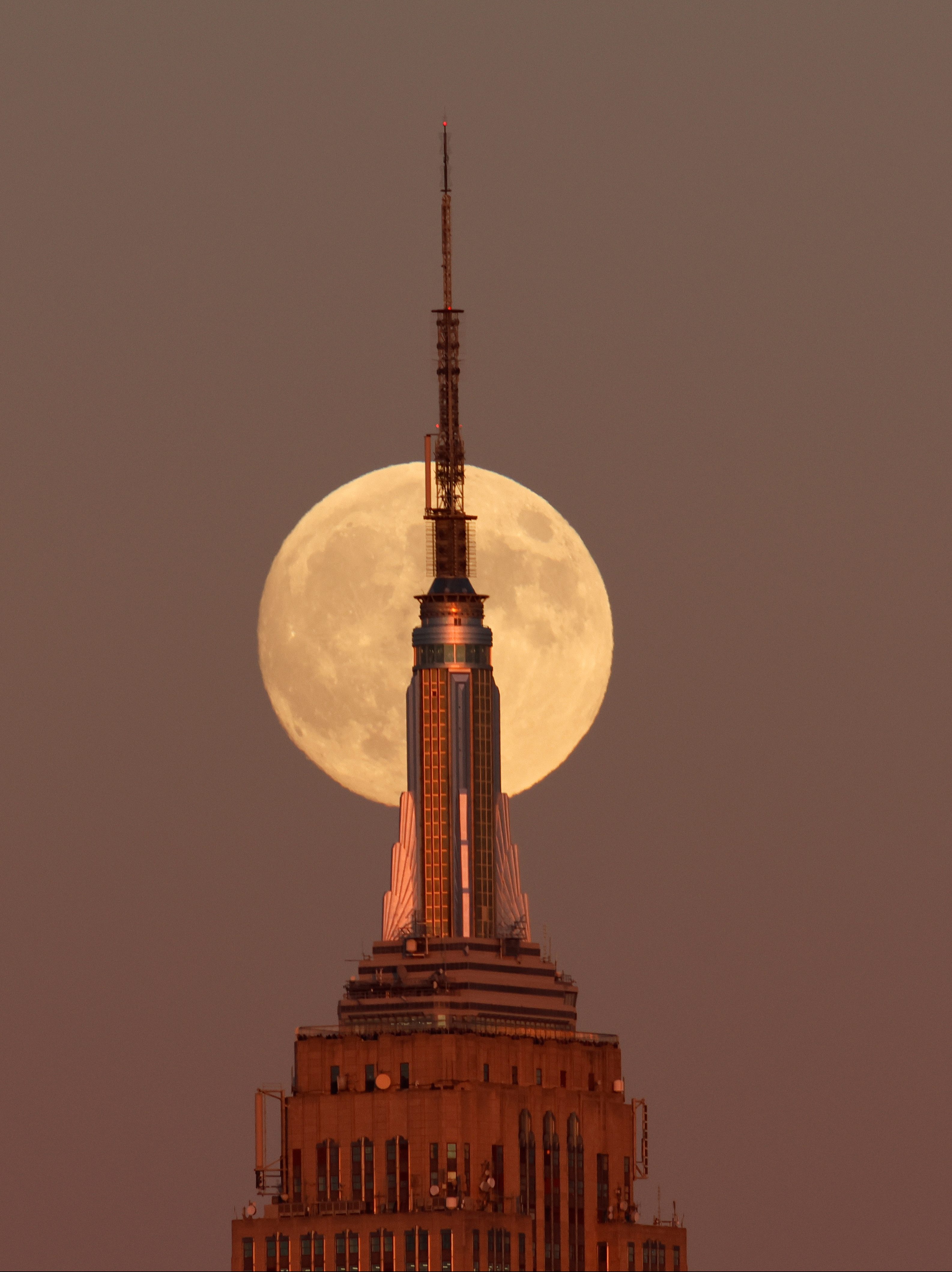 JERSEY CITY, NJ - OCTOBER 16: The Hunter's Supermoon rises behind the Empire State Building in New York City as the sun sets on October 16, 2024, as seen from Jersey City, New Jersey.  (Photo by Gary Hershorn/Getty Images)