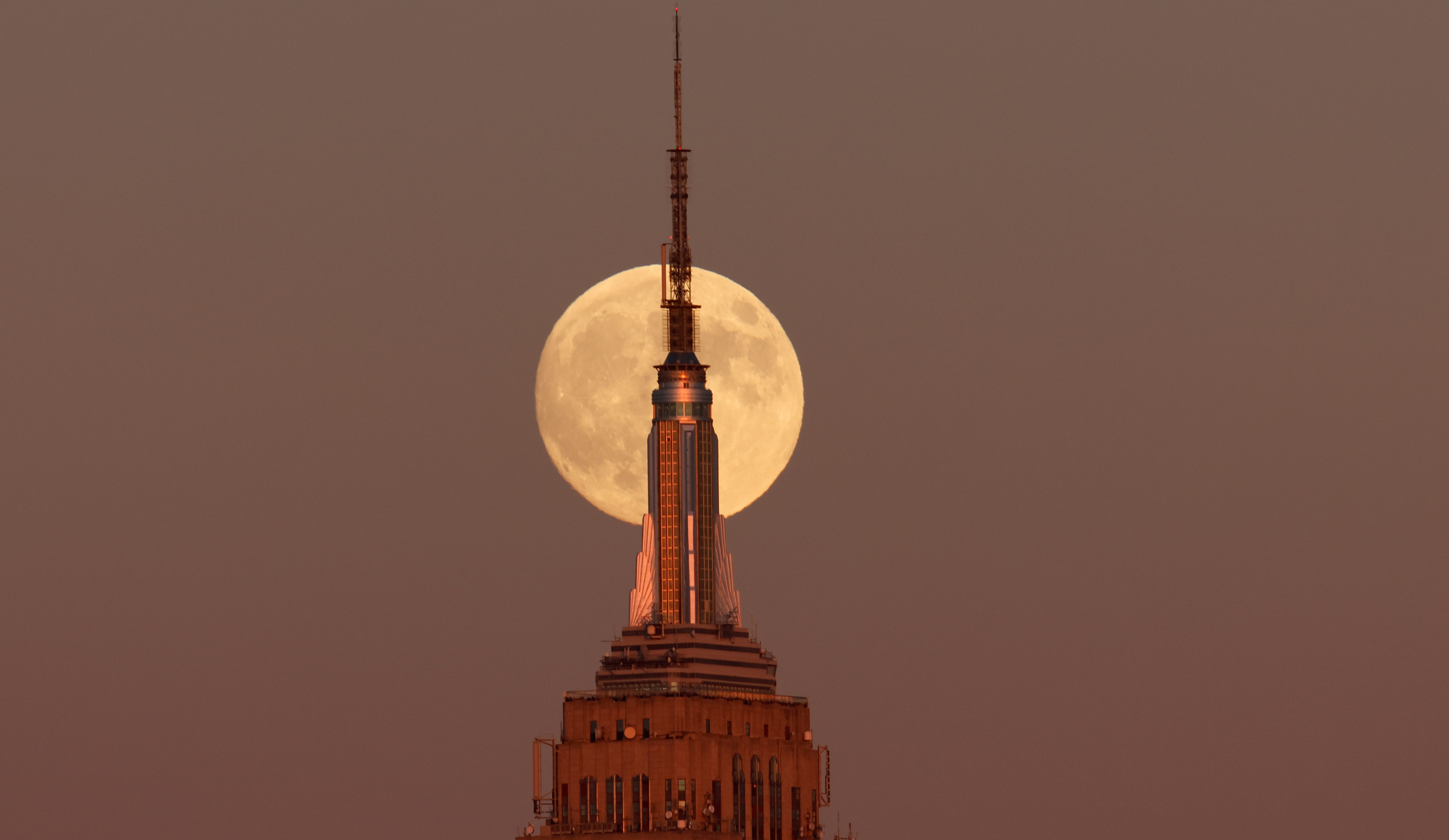 JERSEY CITY, NJ - OCTOBER 16: The Hunter's Supermoon rises behind the Empire State Building in New York City as the sun sets on October 16, 2024, as seen from Jersey City, New Jersey.  (Photo by Gary Hershorn/Getty Images)