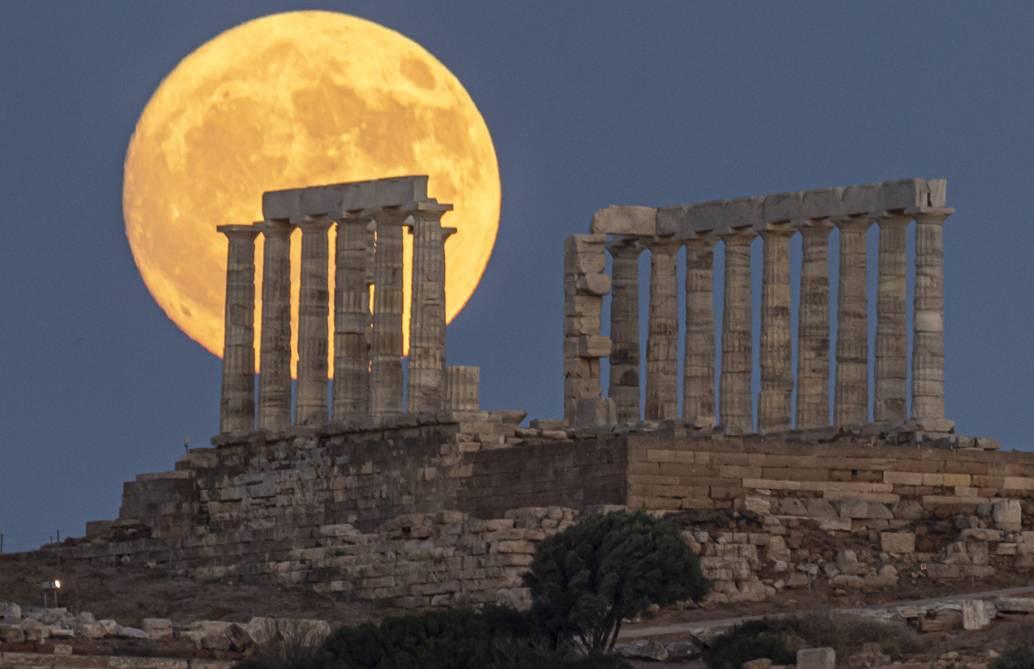 The Full Buck Moon rises behind the ancient Greek Temple of Poseidon on Cape Sounion in Greece on July 20, 2024 (Photo by Nicolas Economou/NurPhoto via Getty Images)